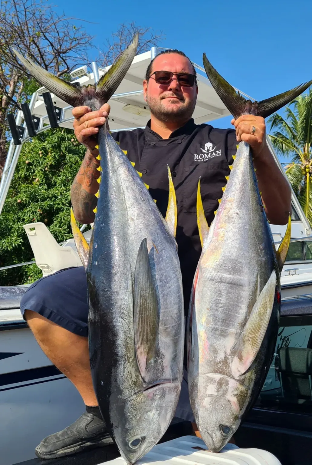 Chef Roman holding two freshly caught tuna aboard a boat in Cayman